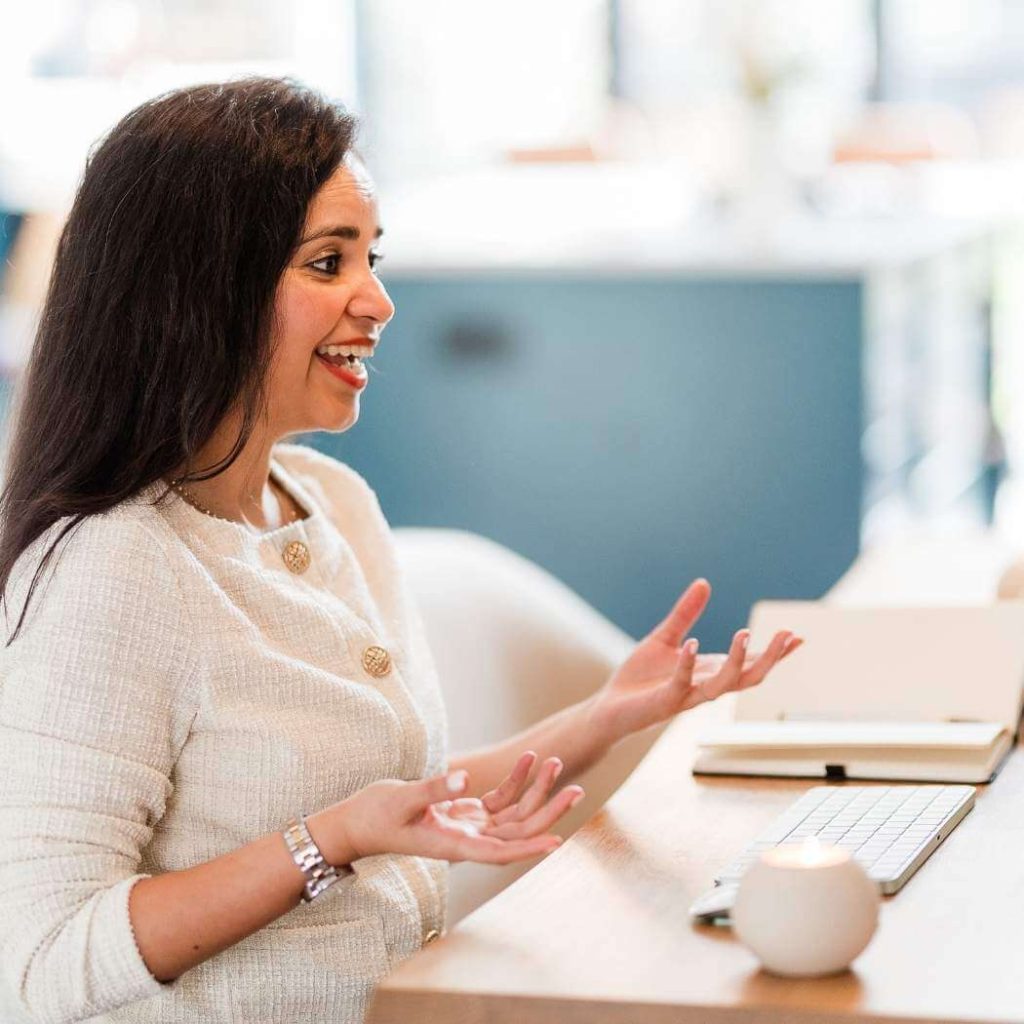 Woman with brown hair sat at a desk with a laptop